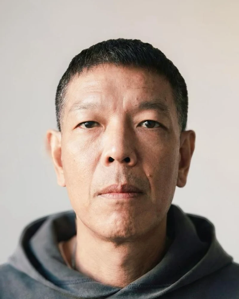 Rozz Sze To, barber at The Cave, with a short tapered crop and clean-shaven face